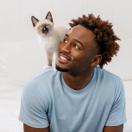 A man with a cat on his shoulder